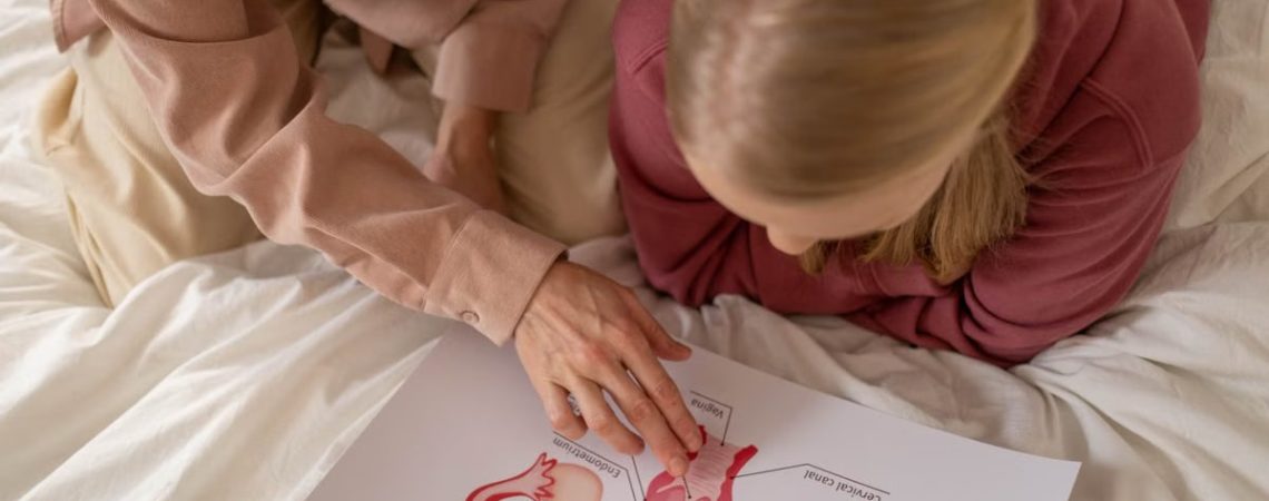 Mother and daughter studying reproductive system illustration for sex education at home.